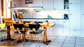A modern kitchen with white cabinets, a wooden dining table, and black chairs.