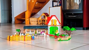 A model train set with buildings, trees, and figures on a tiled floor.