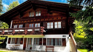 Eine zweistöckige Holzhütte mit Balkon, überdachter Außenbereich und Treppe zum Obergeschoss.