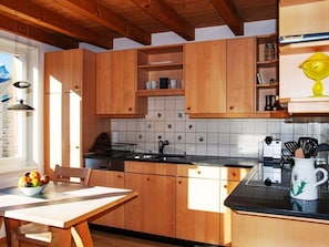 A kitchen with wooden cabinets, a tiled backsplash, a sink, and a countertop.