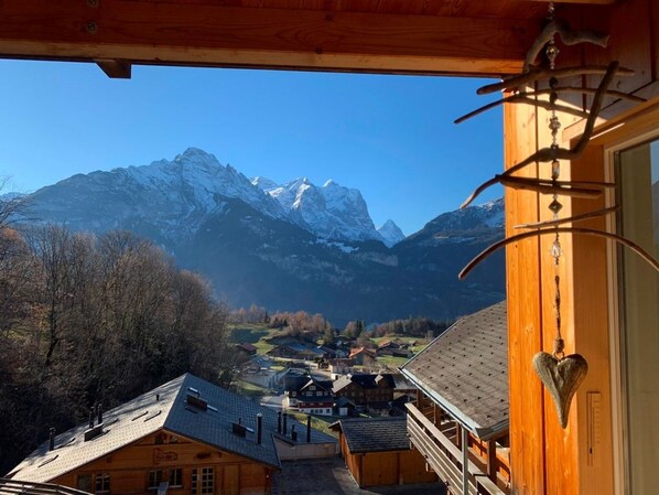 A wooden cabin with a view of snow-capped mountains.