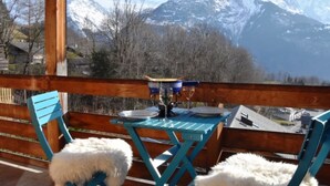 A wooden deck with a table and chairs, overlooking snow-capped mountains. - HasliRent, Wandelhorn 2, (Hasliberg Reuti), by Interhome (Hasliberg)