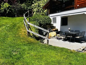 Eine Terrasse mit Gartenmöbeln, einem Holzzaun und einem Gebäude mit einem Fenster.