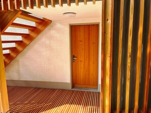 Eine Holztreppe führt zu einer Tür mit einer strukturierten Wand.