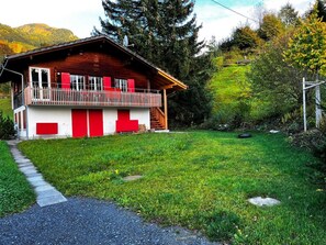 Eine Holzjagdhaus mit roter und weißer Fassade, einem Balkon und einem Rasen.