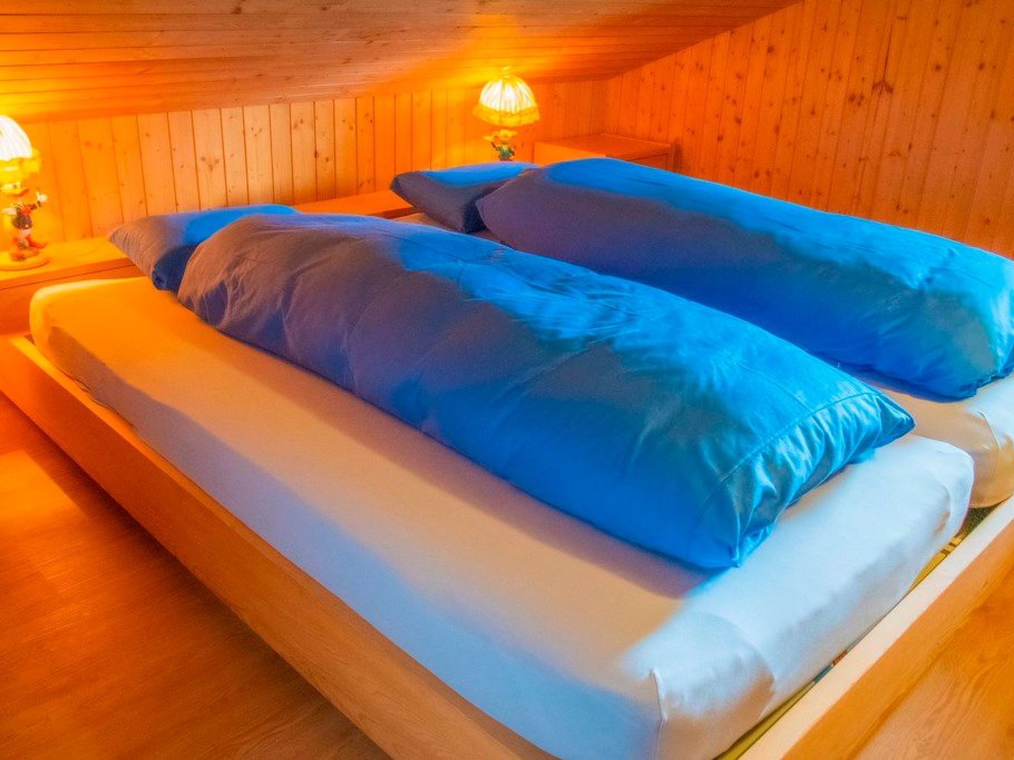 A wooden room with a bed featuring blue bedding.
