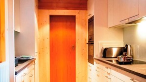 A narrow kitchen with wooden cabinets, a built-in oven, and a coffee maker. - HasliRent, Eiger, (Hasliberg Reuti), by Interhome (Hasliberg)