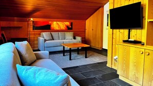 A cozy room with a sofa, a television, and a wooden cabinet. - HasliRent, Eiger, (Hasliberg Reuti), by Interhome (Hasliberg)
