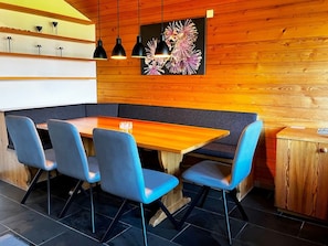 A modern dining area with a wooden table, blue chairs, and pendant lighting.