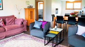 Un salon comprenant un canapé, des fauteuils, une table basse et un coin repas avec des chaises et une table.