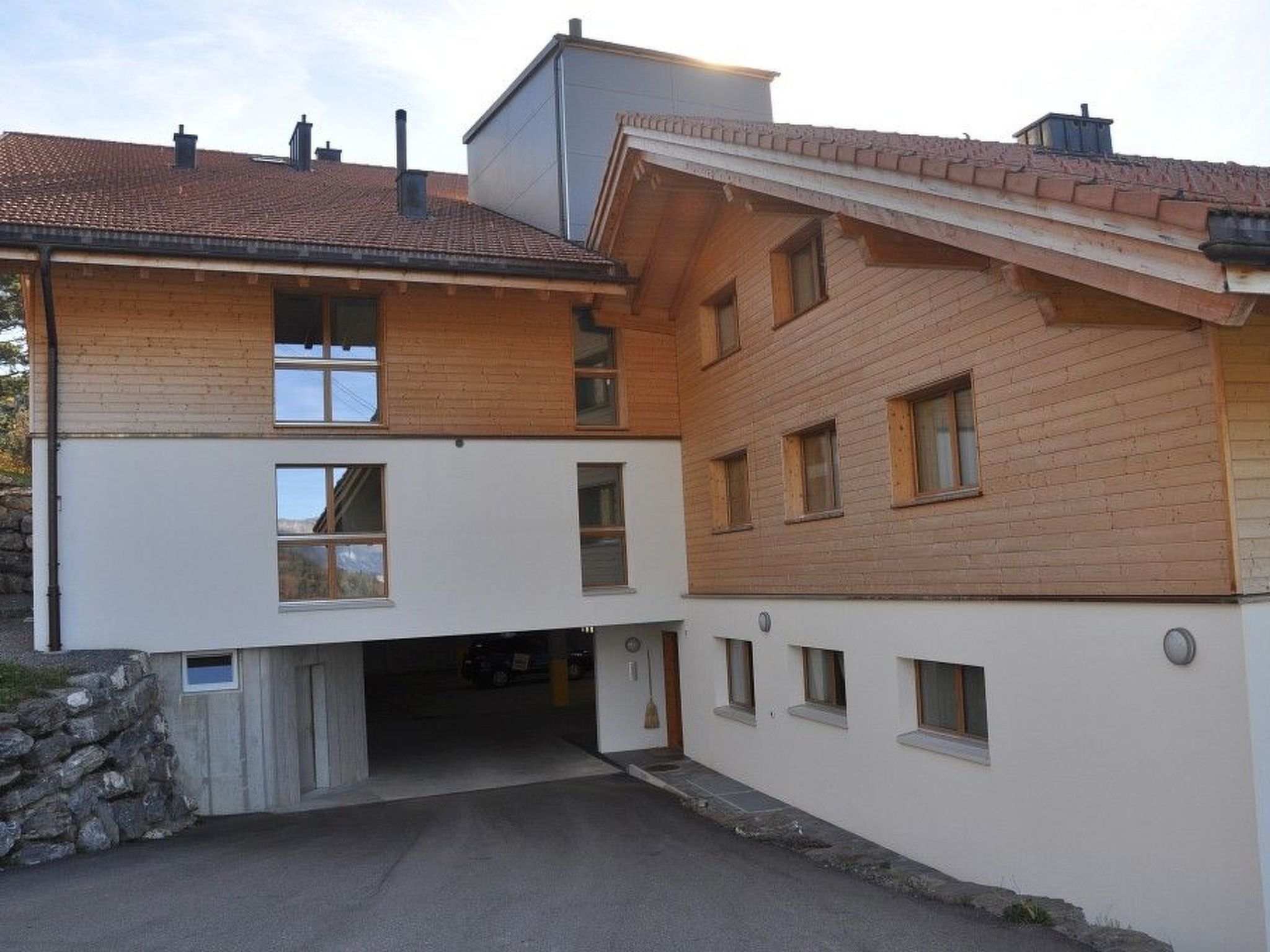 Un bâtiment à deux étages, doté d’un toit en pente, d’une entrée de garage et de fondations en pierre.