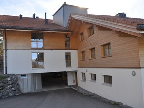 Ein zweistöckiges Gebäude mit Satteldach, Garageneinfahrt und einer Natursteinfundament.
