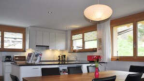 Une cuisine moderne avec des meubles blancs, une table à manger en bois et des chaises noires.