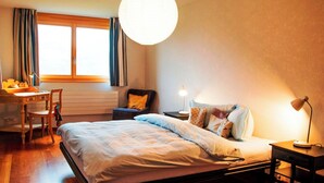 Une chambre à coucher avec un lit, des tables de chevet, un bureau et une chaise.
