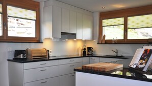 Une cuisine moderne avec des meubles blancs, un plan de travail noir et une planche à découper en bois.