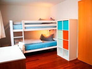Een stapelbed met bureau en opbergunit met kleurrijke vakken.