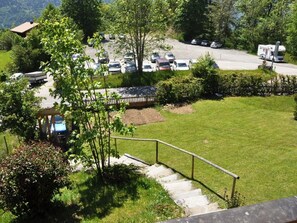 A parking area with multiple cars and a camper van, surrounded by greenery and a building with a sloped roof. - HasliRent, Resti, (Hasliberg Reuti), by Interhome (Hasliberg)