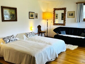A bedroom with a bed, a black sofa, a lamp, and framed pictures on the wall. - HasliRent, Diana, (Hasliberg Reuti), by Interhome (Hasliberg)