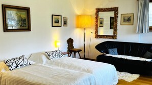 A bedroom with a bed, a black sofa, a lamp, a mirror, and framed pictures on the wall. - HasliRent, Diana, (Hasliberg Reuti), by Interhome (Hasliberg)