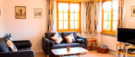Una sala de estar con sofá, sillones, una mesa de centro, televisor y chimenea.