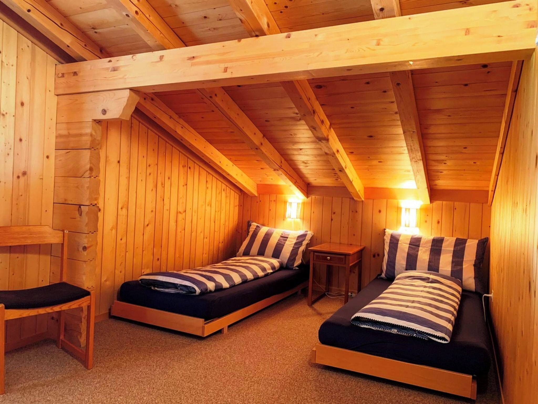 Une cabane en bois avec deux lits simples, un banc et une petite table.