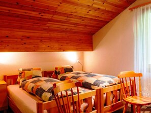 A room with two wooden beds, a wooden chair, and a lamp. - HasliRent, Gibelhüüs 2, (Hasliberg Wasserwendi), by Interhome (Hasliberg)