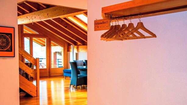 Un intérieur en bois comprenant un escalier, un coin repas et un portant à vêtements.