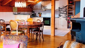 Une cuisine chaleureuse avec des poutres en bois, un coin repas avec une table ronde et des chaises, et une bibliothèque intégrée.