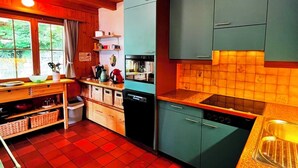 Eine kleine Küche mit Holzausstattung, einem eingebauten Ofen und einer gefliesten Spritzschutzwand.