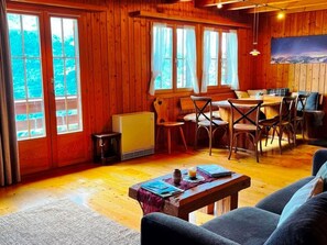 A cozy cabin interior with wooden walls, a dining area, and a sofa. - HasliRent, Cosy 2, (Hasliberg Wasserwendi), by Interhome (Hasliberg)