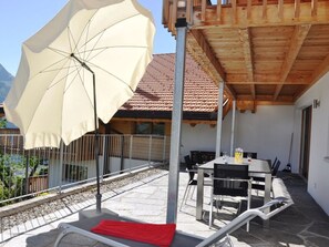 An outdoor patio with a table and chairs, a large umbrella, and a wooden pergola. - HasliRent, Engi West 2, (Hasliberg Reuti), by Interhome (Hasliberg)