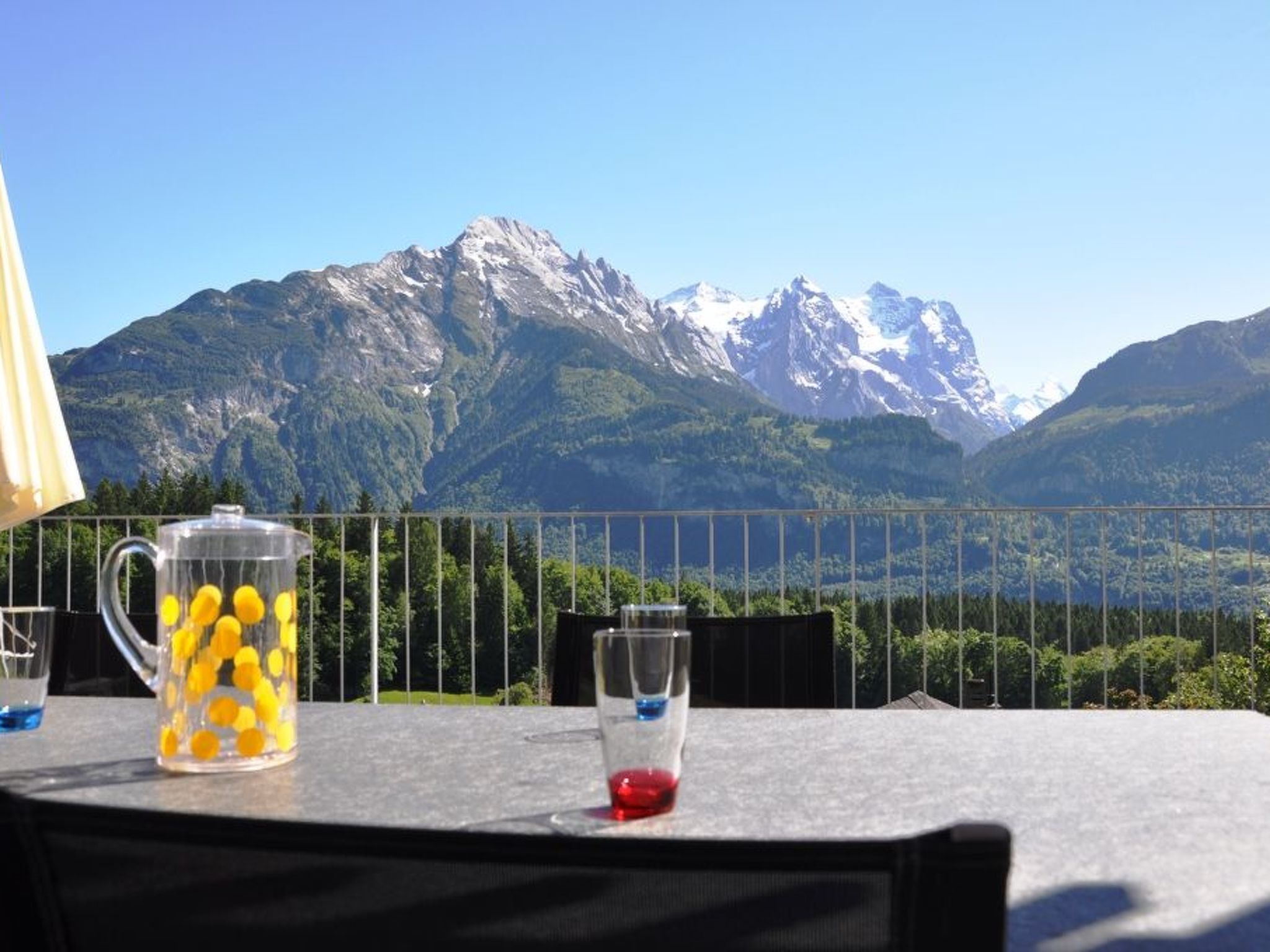 A table with a glass pitcher and a glass, set against a mountain backdrop.