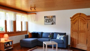 Een woonkamer met een modulaire bank, een bijzettafeltje, een houten kast en een radiator.