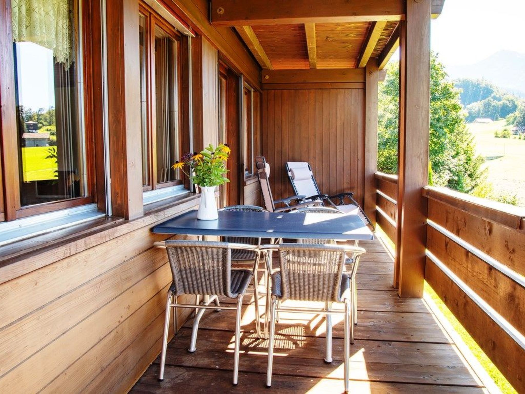 Une terrasse en bois avec une table et des chaises, offrant une vue sur un paysage magnifique.