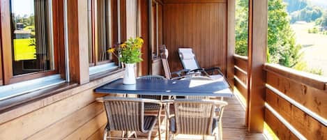 Um deck de madeira com mesa e cadeiras, com vista para uma paisagem deslumbrante.