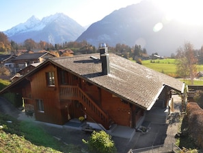 A wooden cabin with a steeply pitched roof, a chimney, and a staircase leading to a porch.