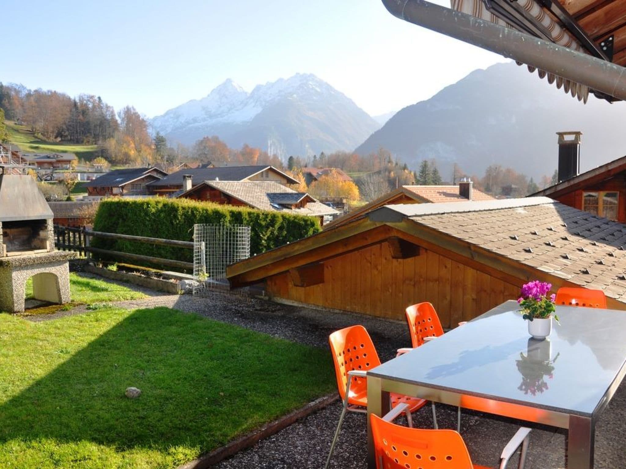 Ein Essbereich mit Tisch und Stühlen, Blick auf die Berge und ein Holzbauten.