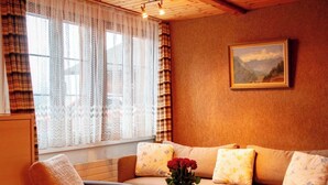 A cozy living room with a sofa, armchair, and a vase with flowers. - HasliRent, Mike, (Hasliberg Reuti), by Interhome (Hasliberg)