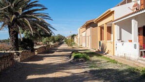 A residential street with houses, a palm tree, and a clear sky. - Casa Vanessa by the Sea (Mandriola)