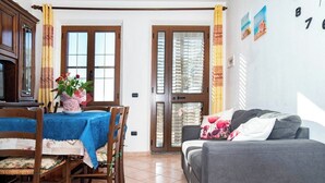 A dining area with a table set for two, a sofa, and a door leading to a balcony. - Casa Vanessa by the Sea (Mandriola)