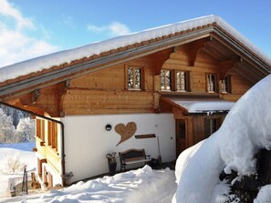 A wooden chalet with a sloped roof, large windows, and a heart-shaped decoration on the wall. - HasliRent, Holiboimi, (Hasliberg Wasserwendi), by Interhome (Hasliberg)
