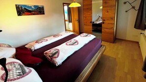 A bedroom with a bed, a bedside table, a lamp, a wardrobe, and a painting on the wall. - HasliRent, Holiboimi, (Hasliberg Wasserwendi), by Interhome (Hasliberg)
