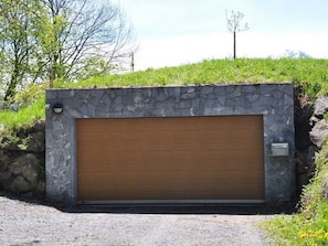 A garage with a stone wall and a wooden door. - HasliRent, Holiboimi, (Hasliberg Wasserwendi), by Interhome (Hasliberg)