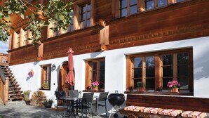 A traditional chalet with a stone patio, outdoor seating, and a barbecue area. - HasliRent, Holiboimi, (Hasliberg Wasserwendi), by Interhome (Hasliberg)