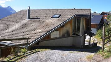 Une maison avec un toit en pente, une cheminée et une petite fenêtre.