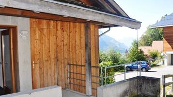 Un bâtiment doté d’une façade en bois, d’un escalier en métal et offrant une vue sur les montagnes en arrière-plan.