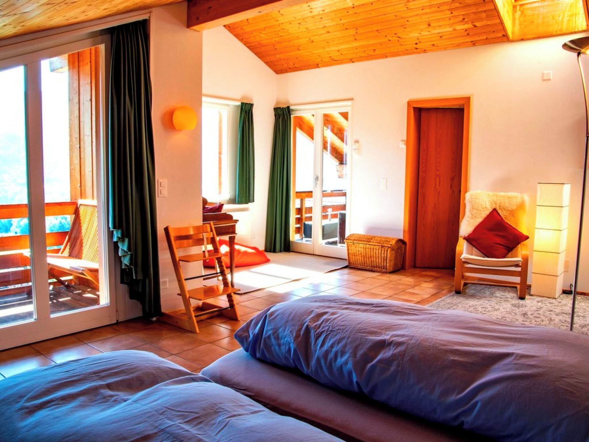 Une chambre à coucher avec un lit, une chaise, une lampe et une vue sur l’extérieur.