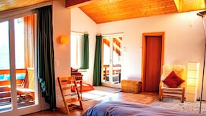 Ein Schlafzimmer mit Bett, Stuhl, Lampe und Blick ins Freie.
