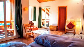 Une chambre à coucher avec un lit, une chaise, une lampe et une vue sur l’extérieur.