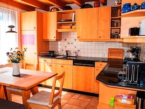 Eine Küche mit Holzschränken, einer schwarzen Arbeitsplatte und einem Esstisch mit Stühlen.